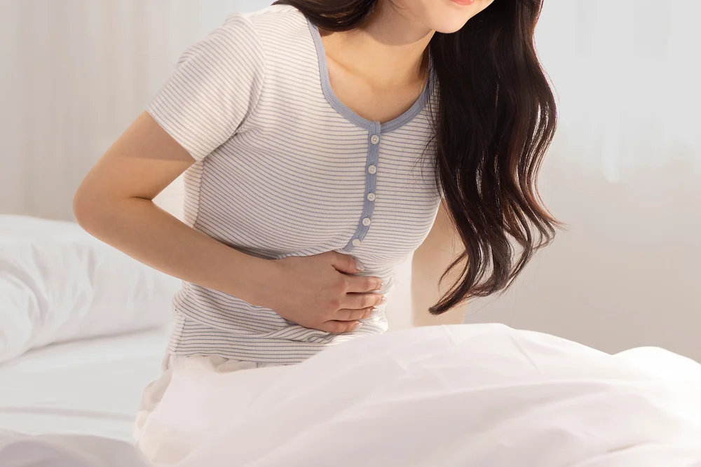 항암부작용병원|복통이나 소화불량으로 배를 움켜쥐고 있는 여성의 모습