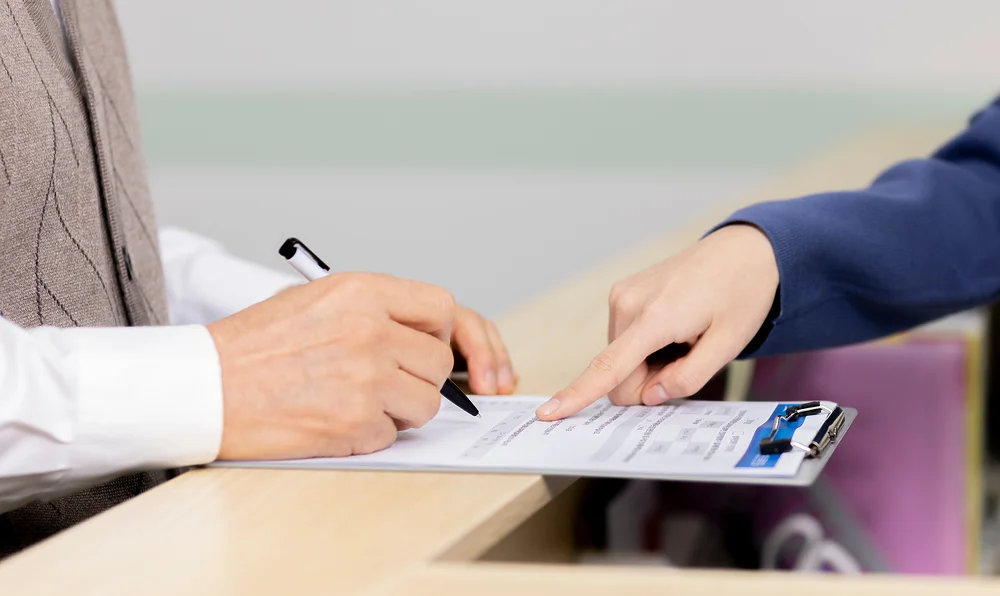 부산 암요양병원 비용|병원이나 사무실 접수처에서 서류에 서명하는 모습